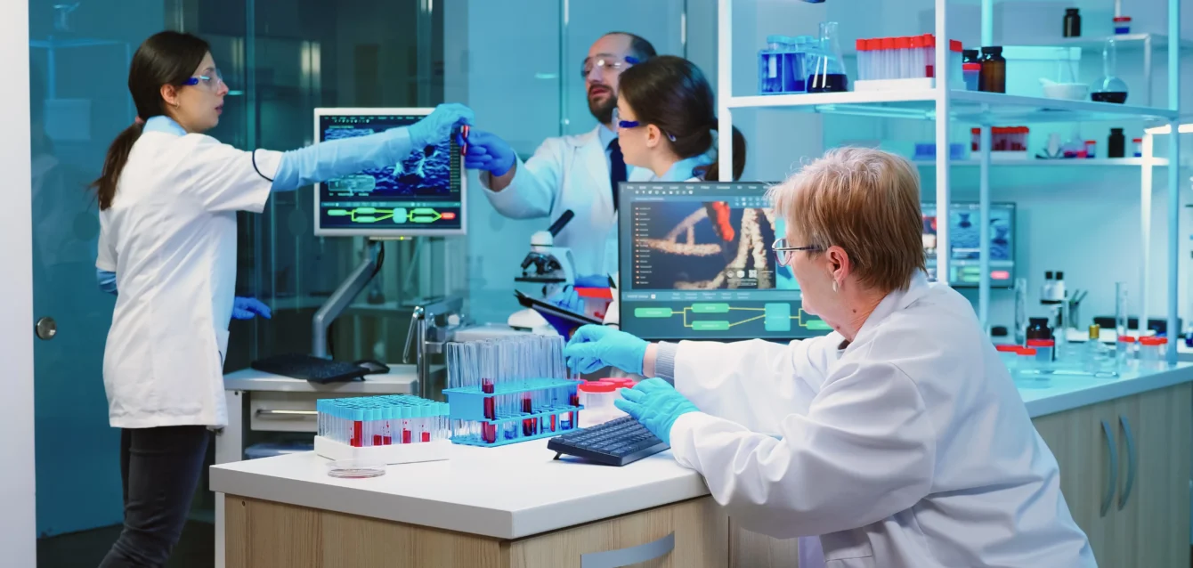 nurse-holding-tablet-computer-with-scientific-informations-while-chemist-using-microscope-with-chemical-test-tube-near
